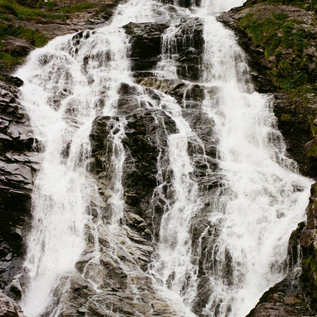 Norsk fossefall. Skummende hvitt vann mot brungrått fjell. Vannkraft er Norges viktigste ressurs.