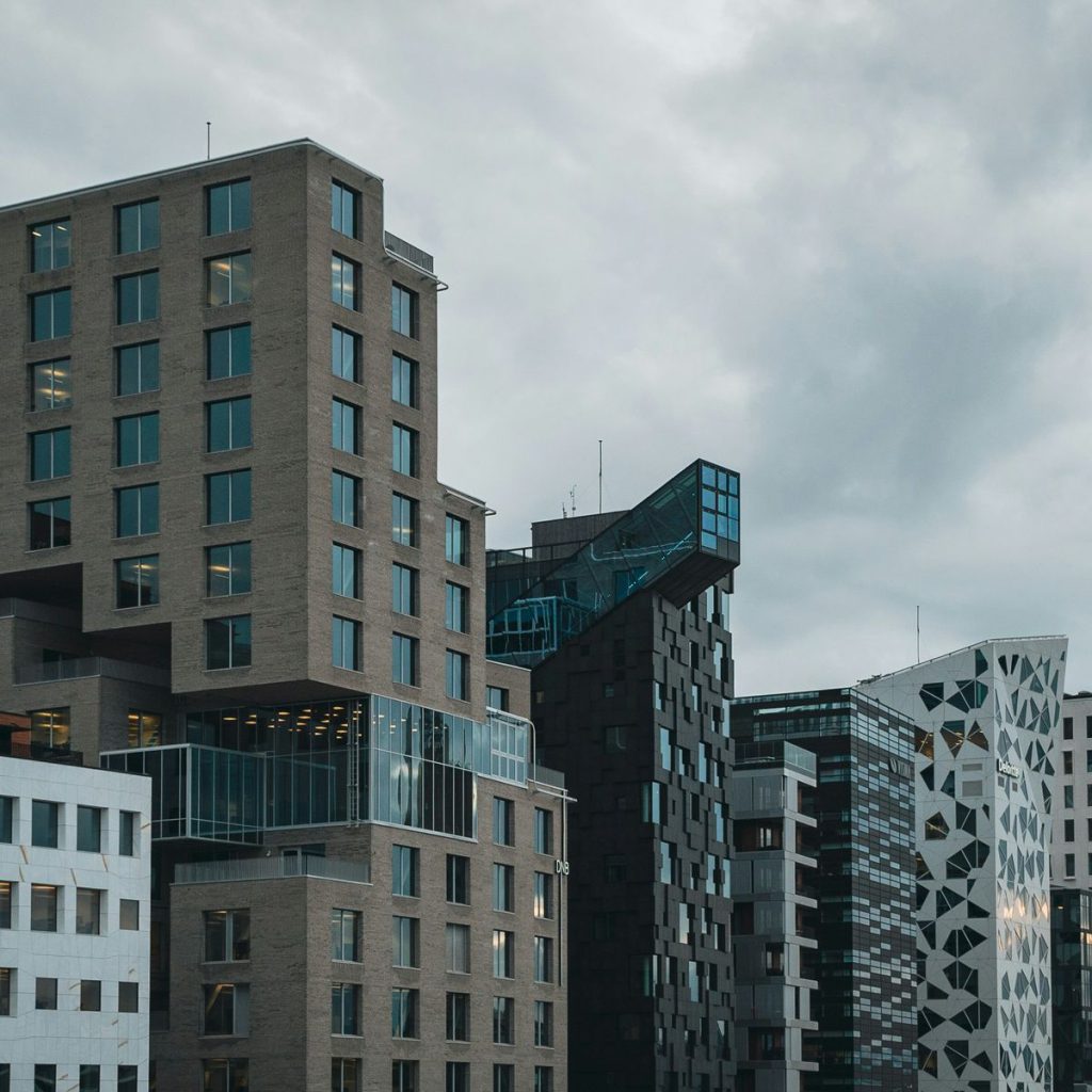 Rad med moderne forretningsbygg i Barcode i Oslo, mot skyet og grå himmel.